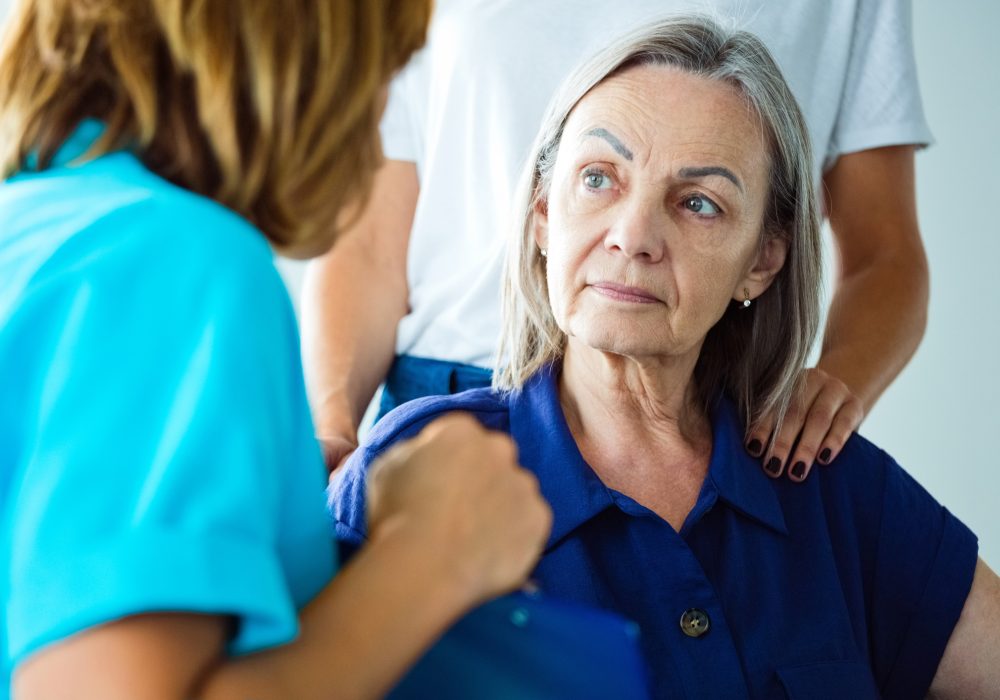 Depressed elderly woman talking with nurse. Close up of face.