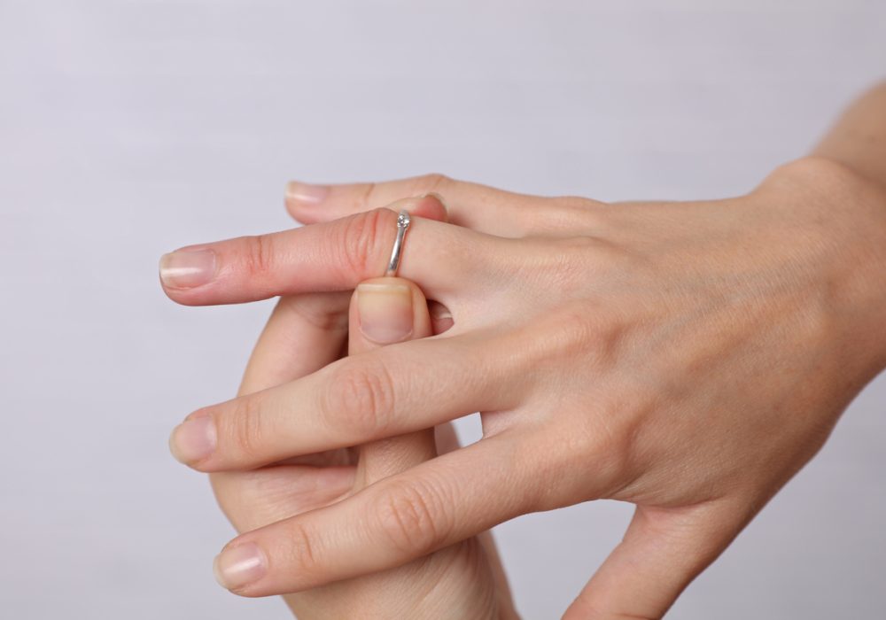 Swollen Hands. Woman traing to remove stuck ring off a swollen finger